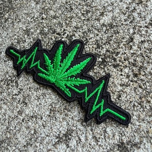 Può includere: Toppa ricamata con una foglia di cannabis verde e un design a battito cardiaco verde su sfondo nero. Per abbigliamento o accessori.