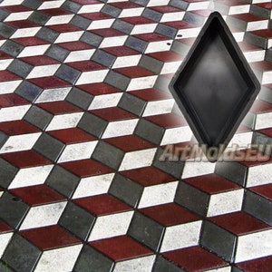 Op de afbeelding: Een zwarte kunststof mal voor het maken van betonnen straatstenen. De mal is diamantvormig en heeft een getextureerd oppervlak. De mal wordt getoond op een afgewerkt betonnen pad met een 3D-patroon.