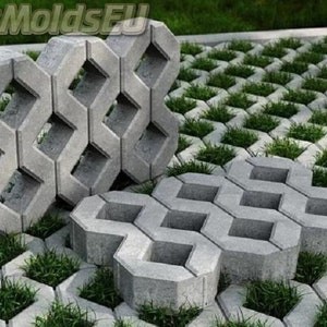 Puede incluir: Pavimentos de hormigón gris con un patrón de rejilla, que permite que el césped crezca a través de las aberturas. Los pavimentos están dispuestos en un patrón repetitivo, creando una superficie de camino o entrada.