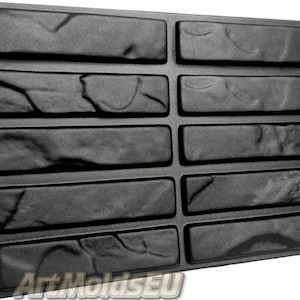 Puede incluir: Un molde de plástico negro para crear un patrón de pared de ladrillo. El molde tiene 12 formas de ladrillo individuales, cada una con una superficie texturizada.