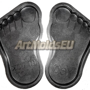 May include: Two black foot-shaped molds for making concrete or resin crafts. The molds are labeled "Foot" and "Left".