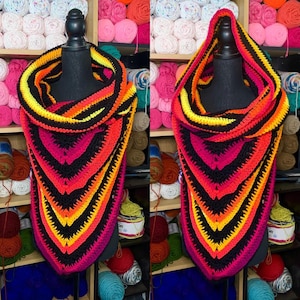 May include: A black, yellow, orange, and red crocheted cowl with a triangular shape. The cowl is made with a variety of stitches and has a textured look.