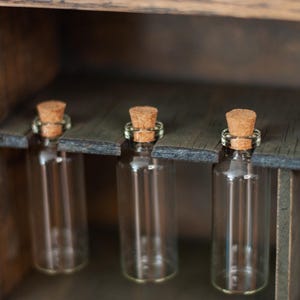 close up view of rustic wooden apothecary-style box with glass vials and jars in various sizes