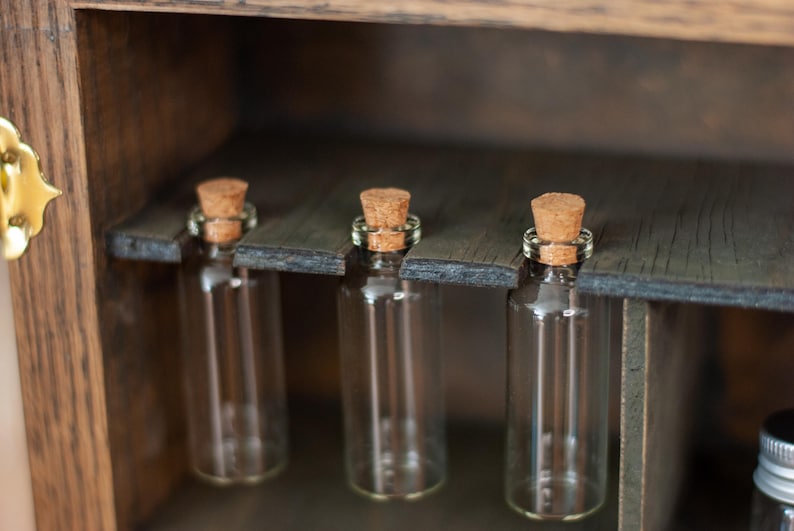 close up view of rustic wooden apothecary-style box with glass vials and jars in various sizes