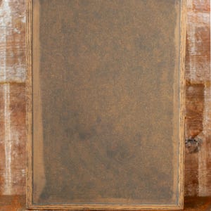 Back view of rustic wooden apothecary box on a wooden tabletop in front of a brick background