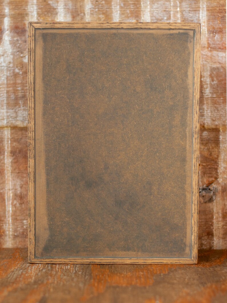 Back view of rustic wooden apothecary box on a wooden tabletop in front of a brick background