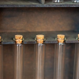 close up view of rustic wooden apothecary-style box with glass vials and jars in various sizes