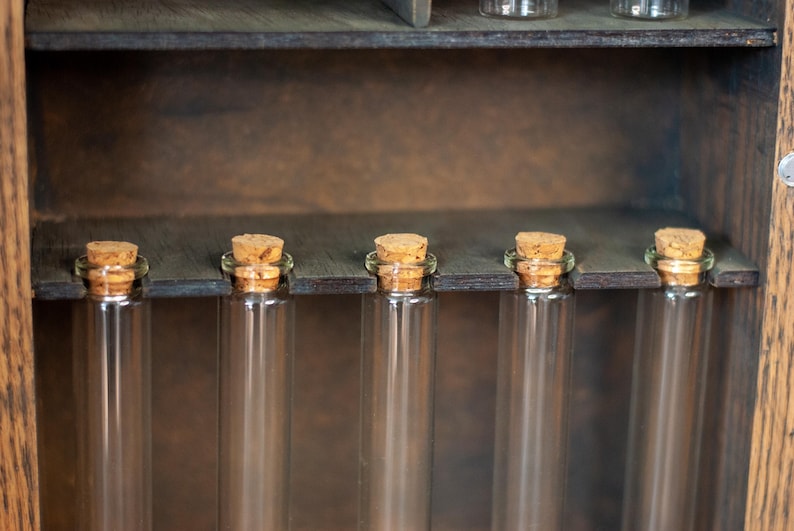 close up view of rustic wooden apothecary-style box with glass vials and jars in various sizes