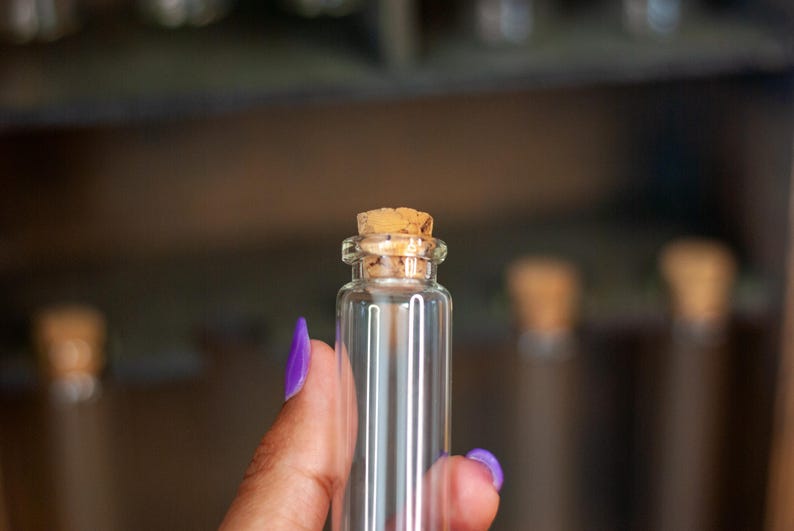 close up view of glass vial with cork lid from a rustic wooden apothecary box