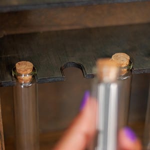 close up view of glass vials with cork lids from a rustic wooden apothecary box