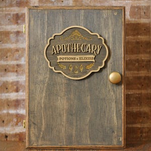 Rustic wooden apothecary-style box with bronze and gold accents with 'Apothecary Potions & Elixirs' label on a wooden background