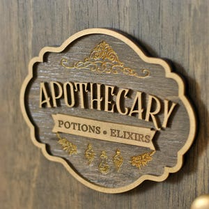 Close up view of rustic wooden apothecary-style box with bronze and gold accents with 'Apothecary Potions & Elixirs' sign