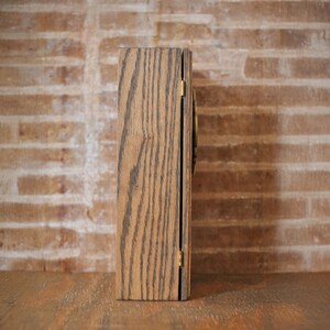 Side view of rustic wooden apothecary box on a wooden tabletop in front of a brick background