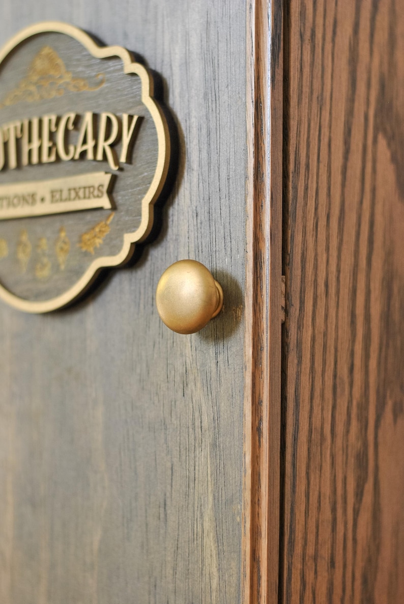 Close up view of bronze gold knob on a rustic wooden apothecary-style box with 'Apothecary Potions & Elixirs' sign