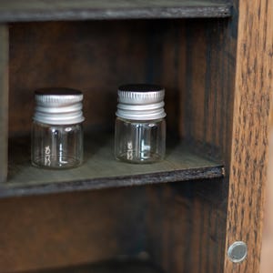 close up view of rustic wooden apothecary-style box with glass vials and jars in various sizes