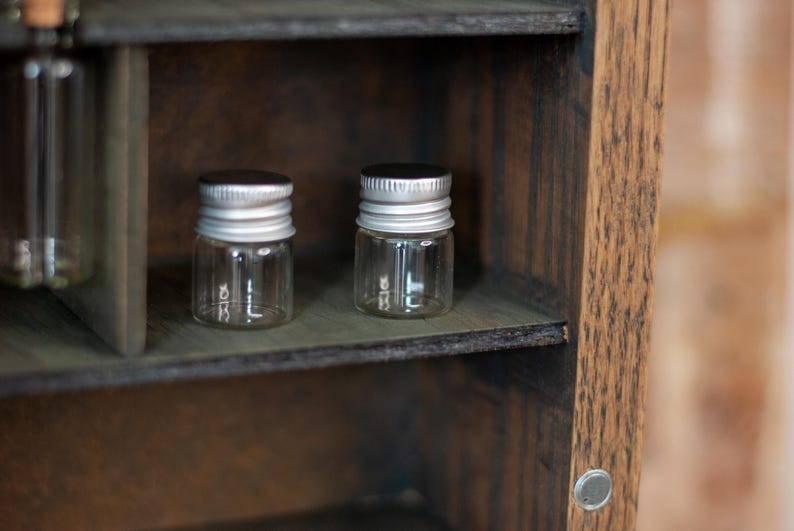 close up view of rustic wooden apothecary-style box with glass vials and jars in various sizes