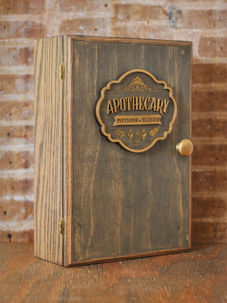 Corner view of rustic wooden apothecary-style box with bronze and gold accents with 'Apothecary Potions & Elixirs' label on a wooden background