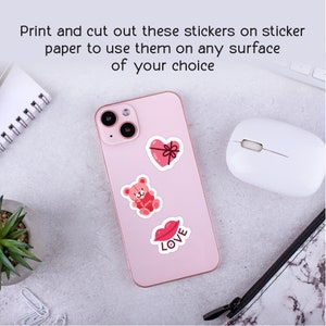 Puede incluir: Un tel&eacute;fono inteligente rosa con tres pegatinas en la parte posterior. Las pegatinas son un coraz&oacute;n rojo con un lazo, un oso de peluche rosa que sostiene un coraz&oacute;n rojo y un labio rojo con la palabra "LOVE" escrita debajo.