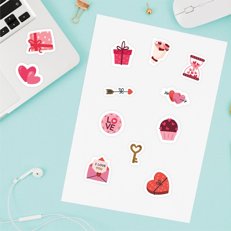 Puede incluir: Una hoja de pegatinas para el D&iacute;a de San Valent&iacute;n con varios dise&ntilde;os, incluyendo corazones, flechas, regalos, cupcakes y un reloj de arena. Las pegatinas son de color rosa, rojo y blanco.