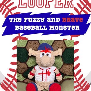 May include: A handmade crochet baseball monster doll, featuring a tan body, blue and red accents, and a white jersey with red details. The doll is set against a backdrop of a baseball graphic and a green and brown hexagonal pattern.