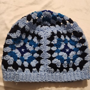May include: A crocheted hat in blue, black, and white with a granny square pattern.