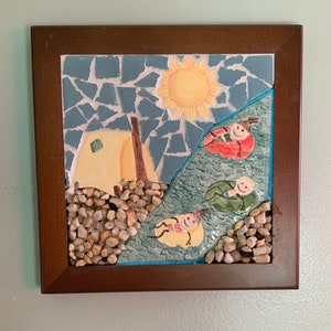May include: A framed mosaic art piece depicting a camping scene. The artwork features a yellow tent, a bright sun, and figures floating in inner tubes on a blue river. The frame is a dark brown color, and the mosaic uses small, irregular tiles.