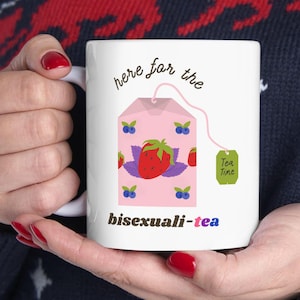 May include: White ceramic mug with a pink tea bag illustration and the text "here for the bisexuali-tea". The tea bag has a strawberry and blueberries on it. The tea bag tag says "Tea Time".