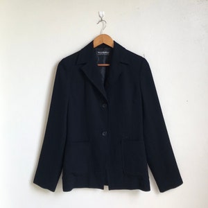 Könnte beinhalten: Ein schwarzer Blazer mit einreihigem Verschluss und zwei Taschen auf der Vorderseite. Der Blazer trägt ein Etikett mit der Aufschrift "Vello Montello".