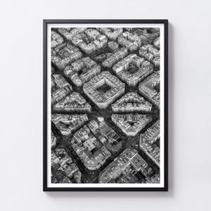 May include: A black and white framed aerial photograph depicting a dense urban cityscape with a grid of city blocks, featuring numerous buildings with flat roofs, interior courtyards, and narrow streets arranged in a geometric pattern.