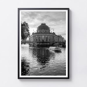 Può includere: Una stampa artistica da parete incorniciata in bianco e nero che raffigura il Bode Museum di Berlino. L'immagine mostra l'edificio a cupola situato sul fiume Sprea con un battello passeggeri che solca l'acqua e un ponte verso la riva.