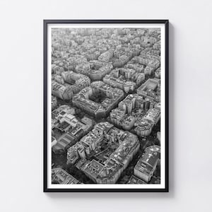 May include: A black and white framed aerial photograph showing a dense urban cityscape with numerous multi-storey buildings arranged in block patterns, featuring flat rooftops, internal courtyards, and narrow streets throughout the city grid.