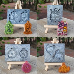 Könnte beinhalten: Eine Sammlung von vier Bildern mit Kunstharz-Kunstwerken mit Cartoon-Charakteren und ihren entsprechenden Formen. Die Stücke umfassen einen grünen Alien, einen orangefarbenen Grabstein, eine rosa Figur mit japanischem Text und einen rosa Donut. Die Formen sind grau.