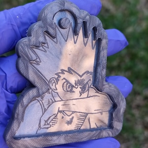 Könnte beinhalten: Ein schwarz-weißes, in Holz gebranntes Bild eines Comic-Charakters mit stacheligem Haar und einem ernsten Ausdruck. Der Charakter trägt ein Hemd und hat seinen Arm über die Brust gelegt.