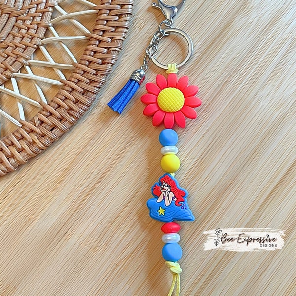 Adorable, handmade, and so vividly colored, silicone mermaid keychain! Lobster claw clasp, yellow suede cord, red focal flower bead.