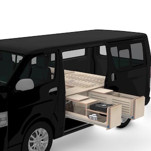 Pode incluir: Uma carrinha preta com a porta lateral aberta, revelando um interior de madeira personalizado. O interior inclui gavetas retráteis e uma estrutura de cama. As gavetas contêm um pequeno fogão e espaço de armazenamento. A carrinha está estacionada numa superfície branca.