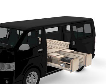 May include: A black van with the side door open, revealing a custom wooden interior. The interior includes pull-out drawers and a bed frame. The drawers contain a small stove and storage for supplies. The van is parked on a white surface.
