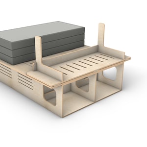 May include: A wooden storage shelf with three compartments and a top shelf. The top shelf has a slatted design and is holding a stack of three gray cushions.