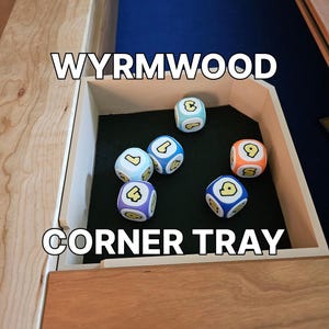 May include: A wooden corner tray with the text "WYRMWOOD CORNER TRAY" in white. The tray contains six colourful dice with rounded edges, each displaying a different number and symbol. The dice are blue, orange, and purple.