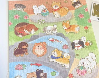 May include: A sheet of stickers featuring various dog breeds in a whimsical, illustrated style. The stickers showcase dogs of different colors and sizes, set against a backdrop of a pond, flowers, and a grassy area. The stickers have a textured, paper-like appearance.