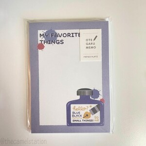 May include: A purple notepad with the text "My Favorite Things" and a small sticker that says "OTE GARU MEMO PAPIER PLATZ". The notepad has a blue ink bottle illustration with the text "hello?* BLUE BLACK So SMALL THINGS! m".
