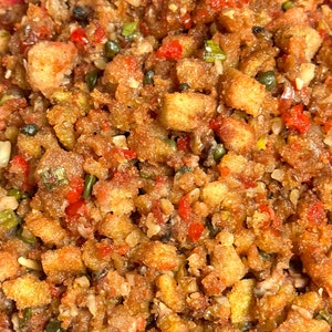 May include: Close-up of a bowl of stuffing with a mixture of toasted bread cubes, red peppers, green onions, and herbs.