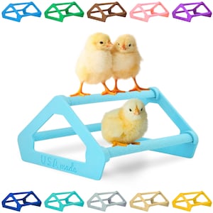 May include: A blue plastic chick perch with two levels and a 'USA Made' inscription. Three yellow chicks are perched on the top level. The perch is available in ten different colors.