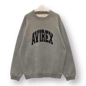 Pode incluir: Um moletom cinza mesclado com a palavra "AVIREX" impressa em letras pretas grandes e arqueadas no peito. O moletom tem gola redonda e mangas compridas. A pe&ccedil;a de roupa est&aacute; pendurada em um cabide branco.