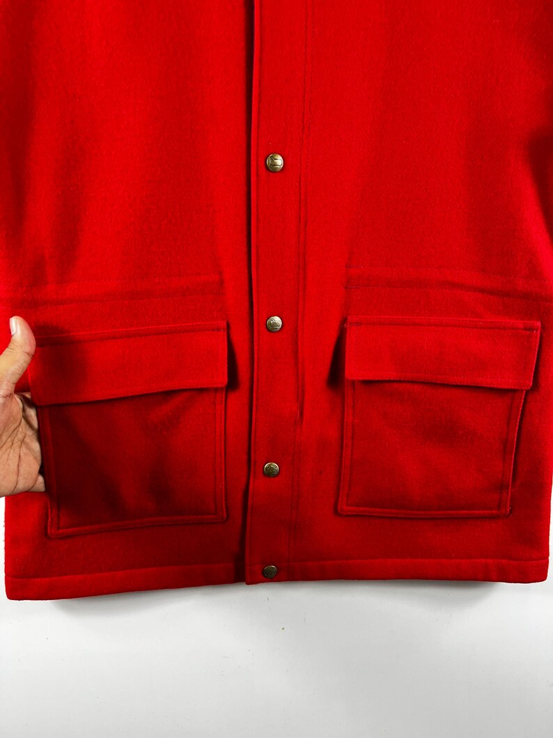 May include: A red wool jacket with a button closure and two large flap pockets on the front.