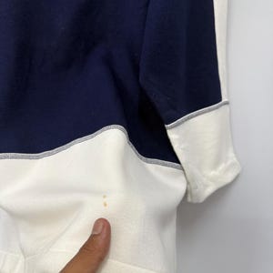 Puede incluir: Una sudadera azul marino y crema. La sudadera presenta un dise&ntilde;o de bloques de color con azul marino en la parte superior y crema en la inferior. Los pu&ntilde;os de las mangas son crema con ribete azul marino.