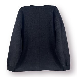 Op de afbeelding: Een zwart fleece sweatshirt met een ronde hals en lange mouwen.