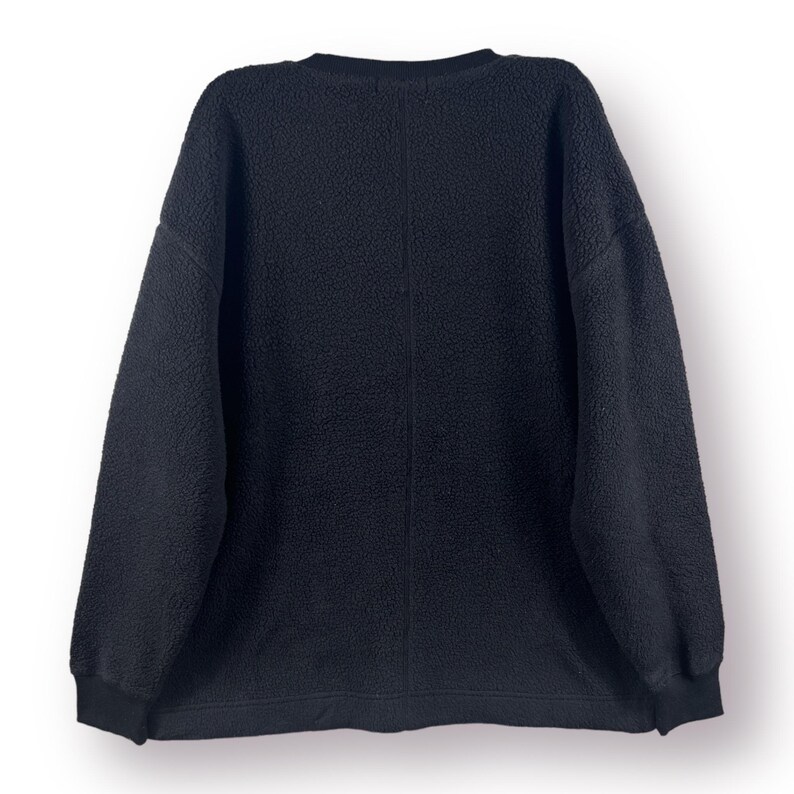 Op de afbeelding: Een zwart fleece sweatshirt met een ronde hals en lange mouwen.