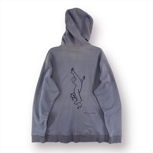 May include: A grey hoodie with a drawstring hood and a kangaroo pocket. The back features a black line drawing of a person skateboarding with arms raised. The text "Don't lose your inner child" is below the graphic.
