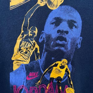 Puede incluir: Sudadera azul marino con un gr&aacute;fico de baloncesto. El dise&ntilde;o presenta a un jugador de baloncesto en acci&oacute;n, la palabra "JORDAN" en ne&oacute;n rosa y el logotipo de Nike. La imagen incluye un retrato de un jugador de baloncesto.