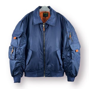 May include: A navy blue bomber jacket with orange zipper pulls and pockets. The jacket has a  "FIRE FOX" label on the left side of the collar.